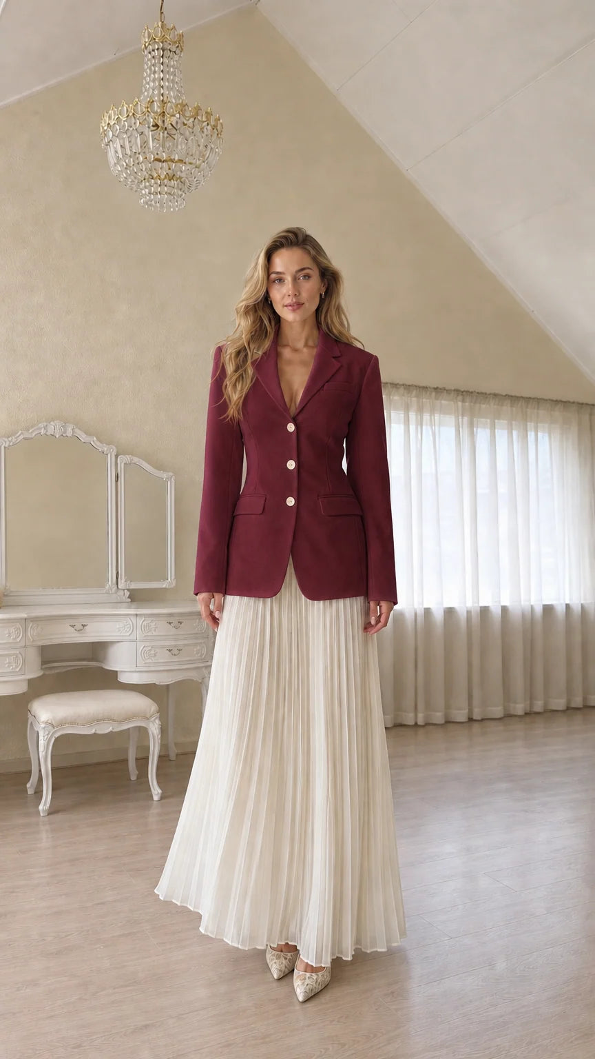 Full length view of a woman wearing a burgundy tailored blazer and pleated skirt