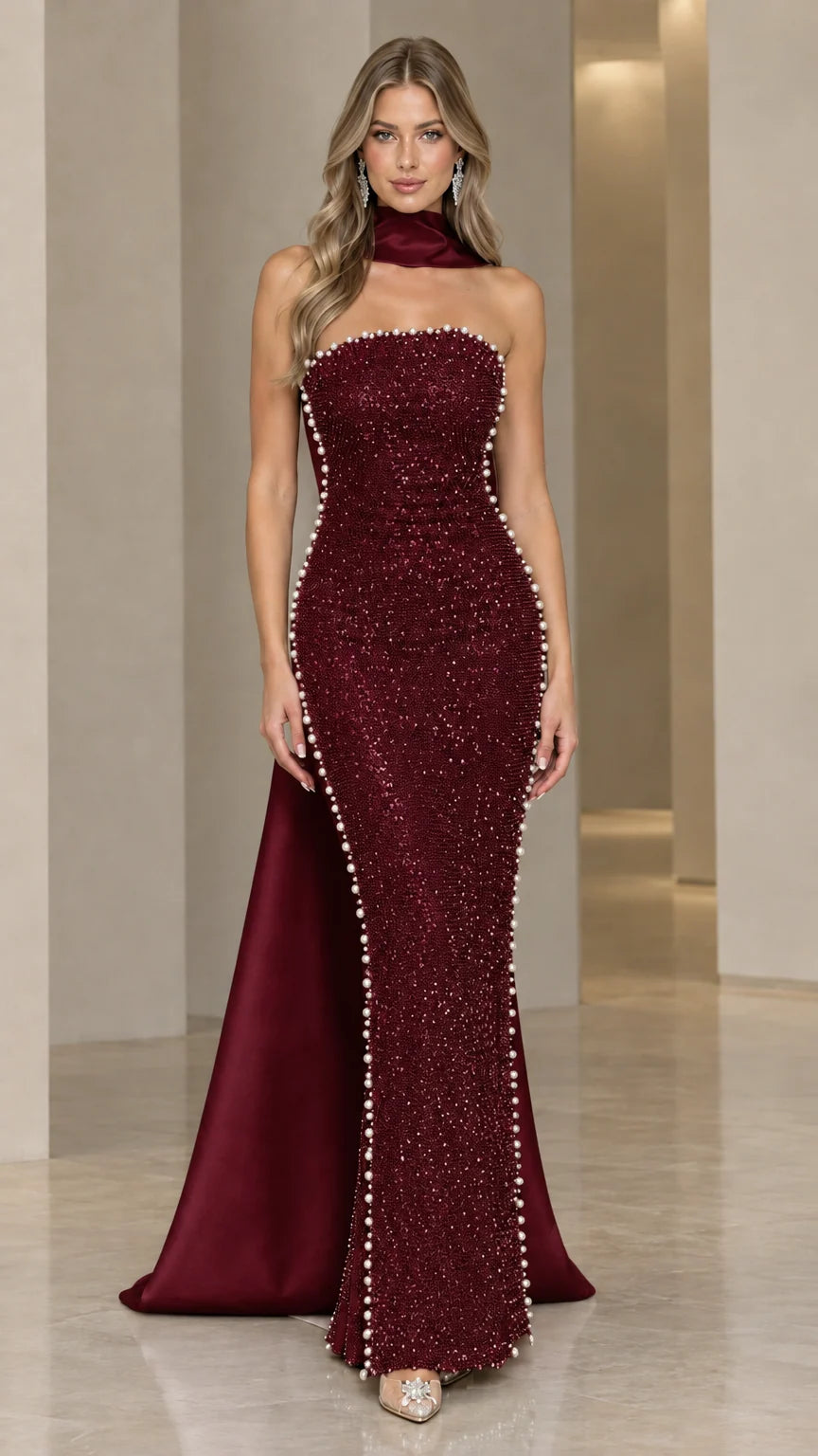 Model wearing deep burgundy red beaded formal gown with flowing satin-look cape