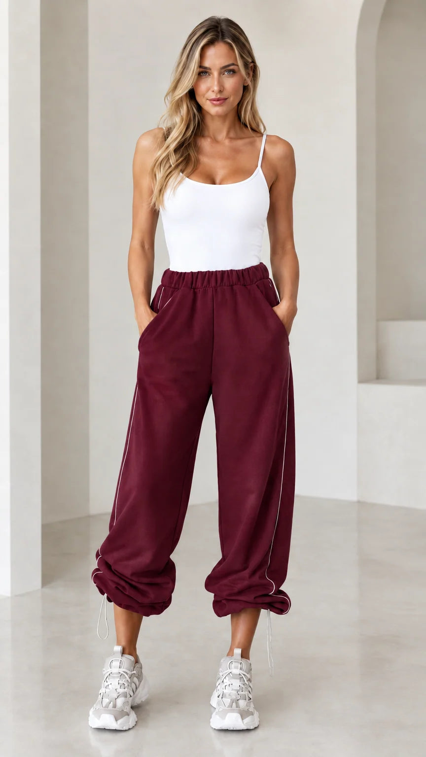 Model wearing burgundy wine red relaxed joggers with side piping