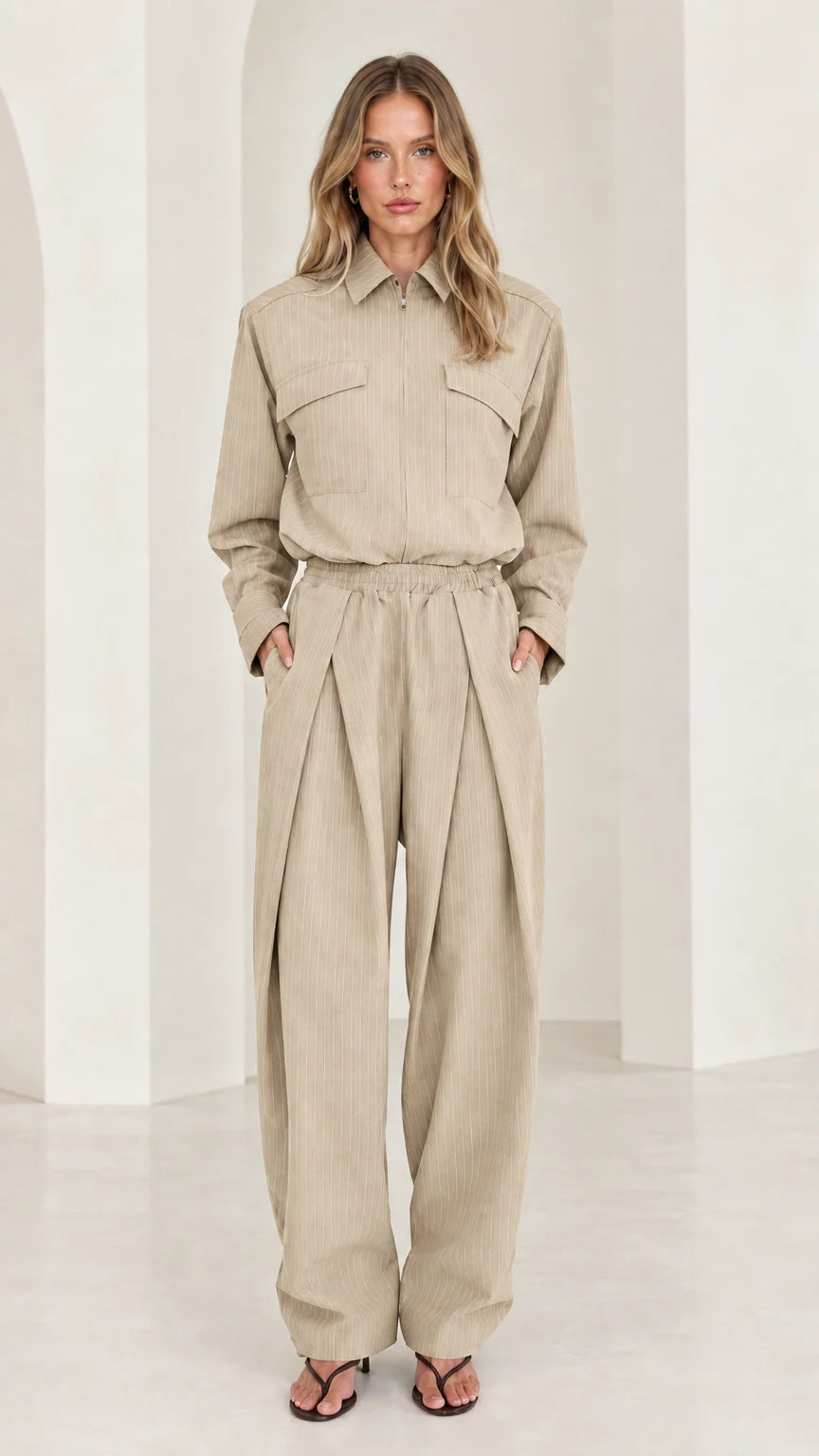 Front view of model wearing beige long sleeve pleated wide-leg jumpsuit