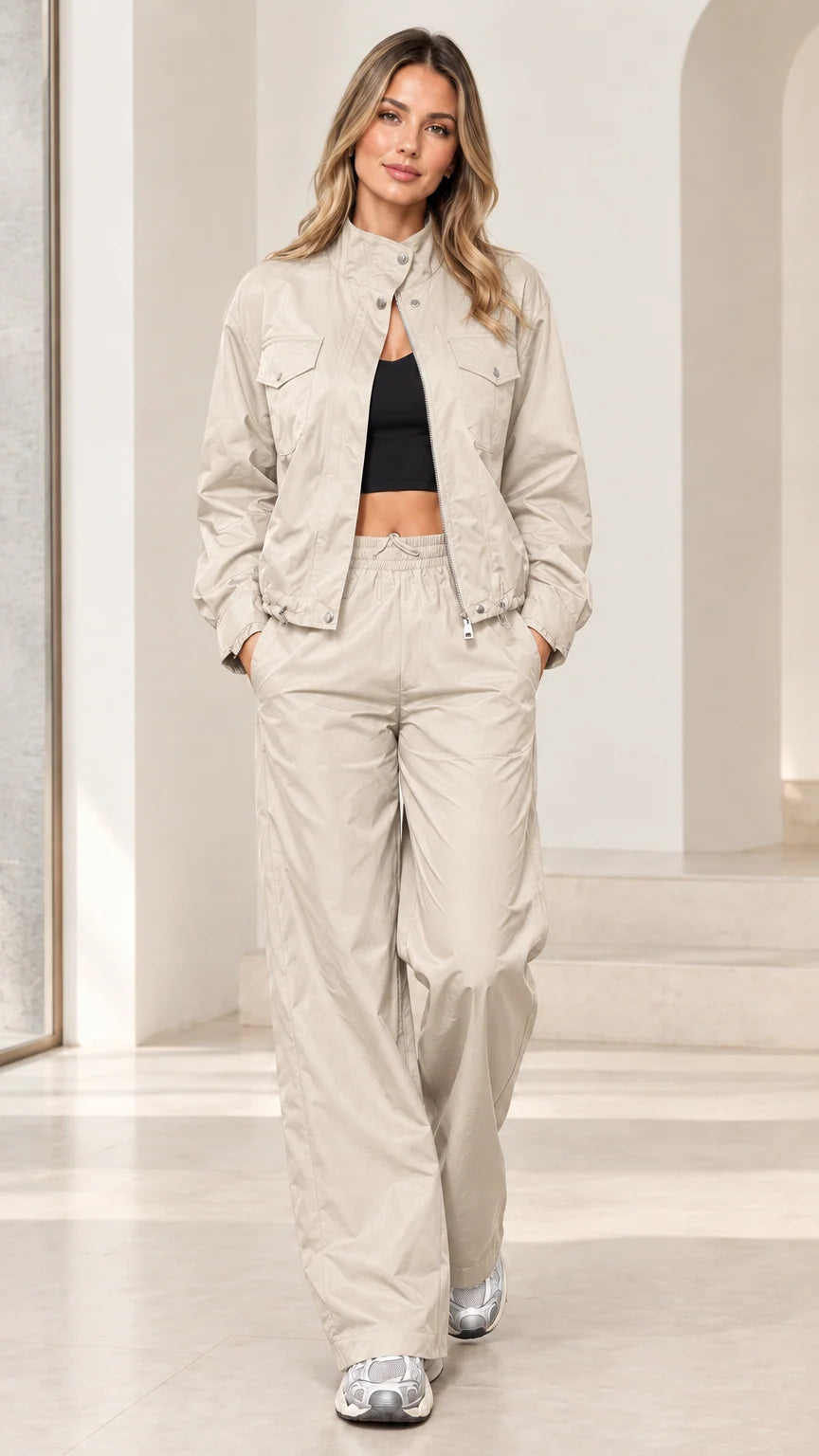 Full-length studio shot of woman wearing beige sand zip-up windbreaker track set